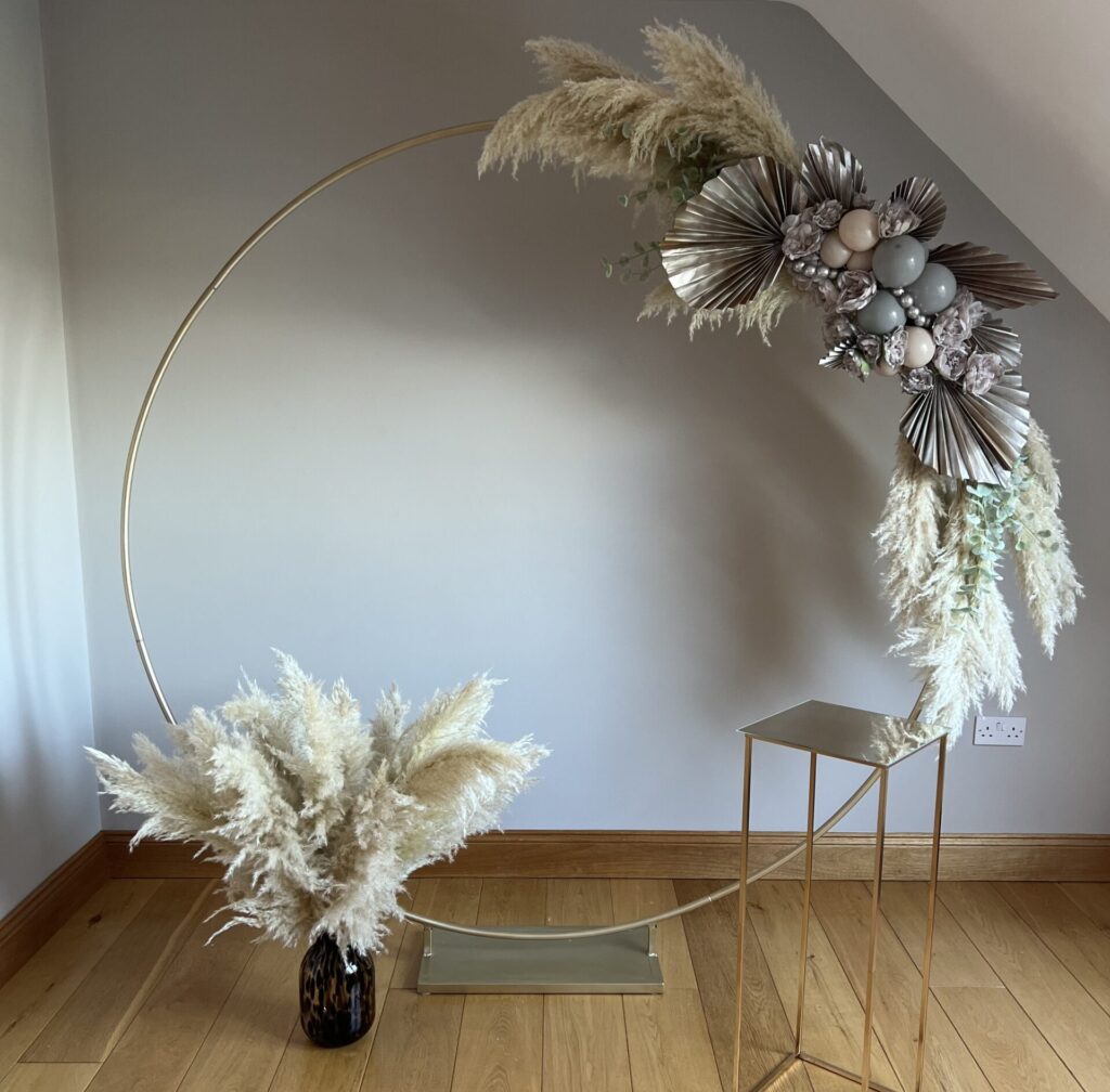 Items to hire. An arch, vase with pampas grass and golden side table with mirror top.